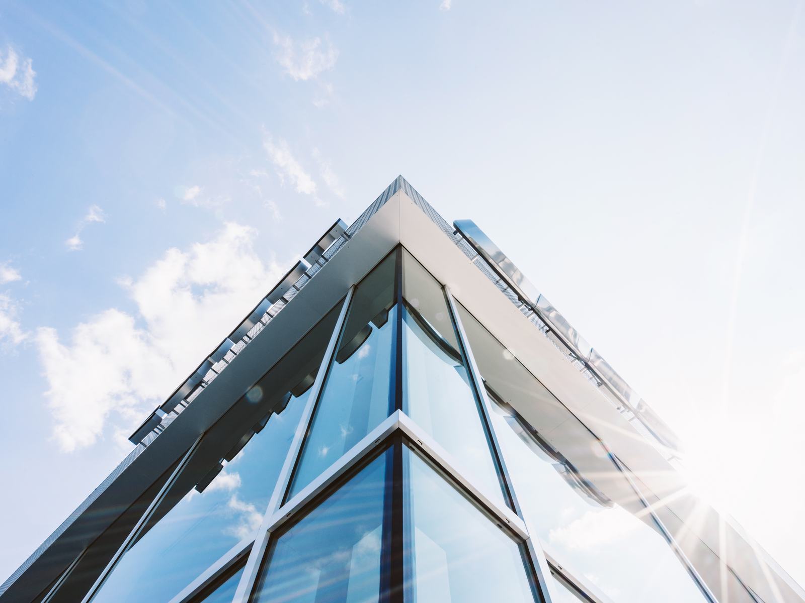 The glass corner of a building against a bright sky