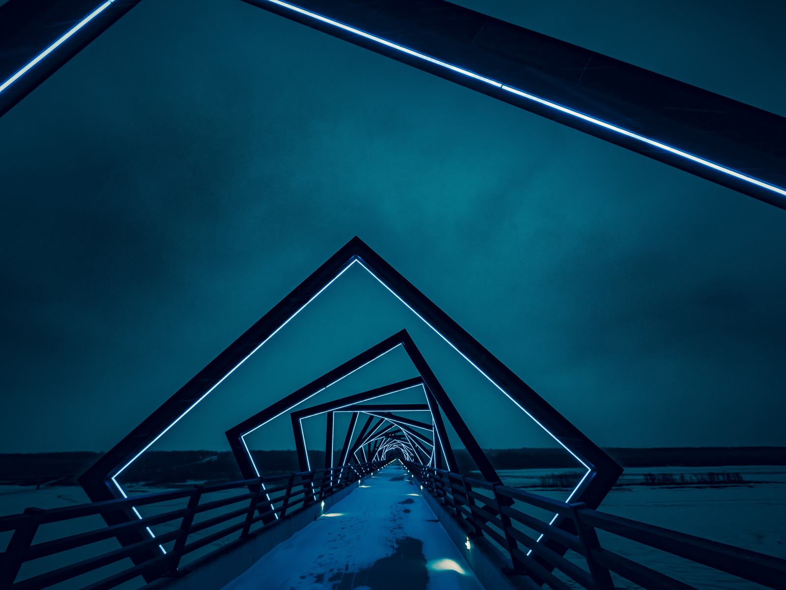 A walkway framed by lines of blue light at night