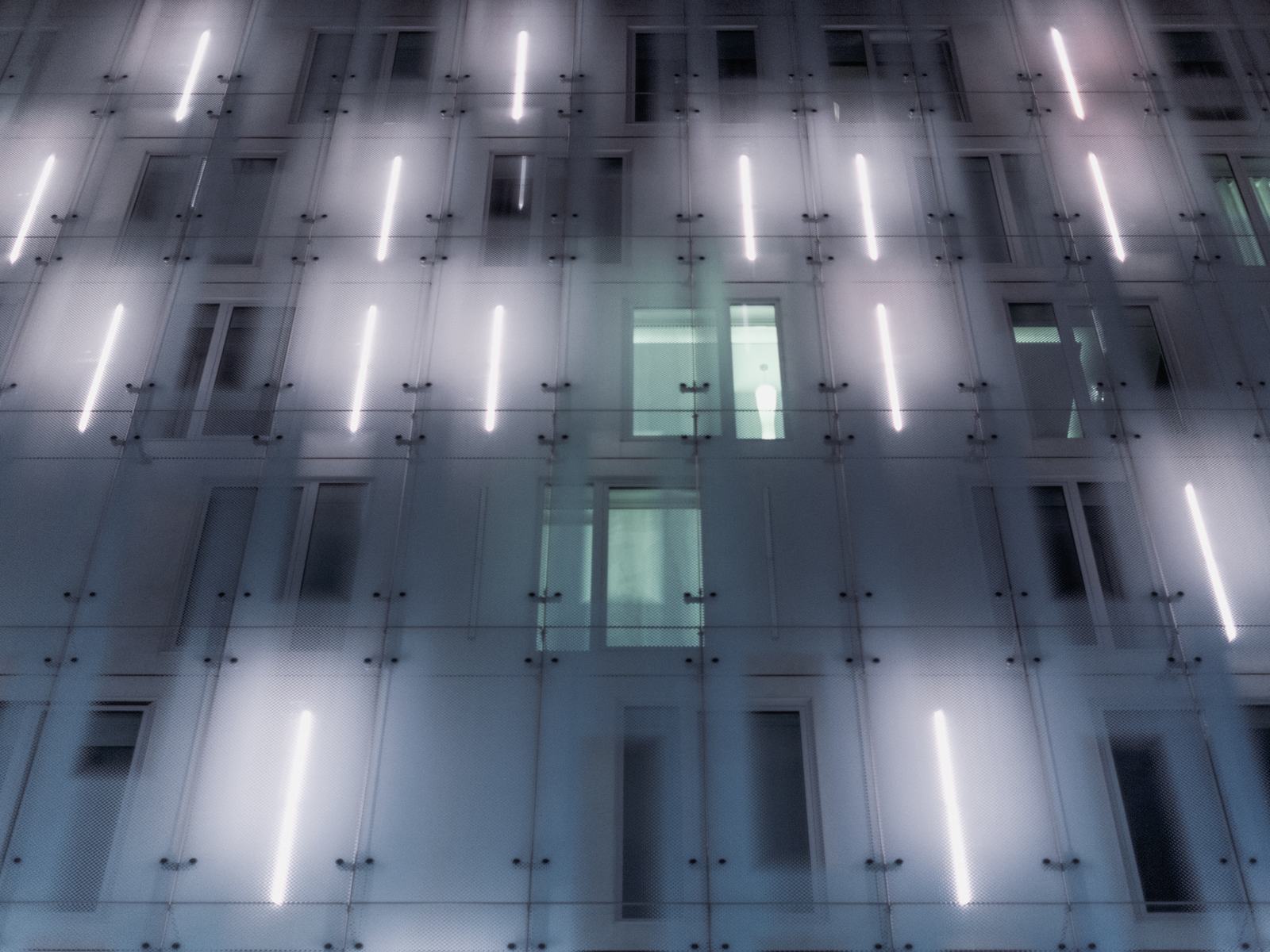 A building facade with narrow strips of light at night